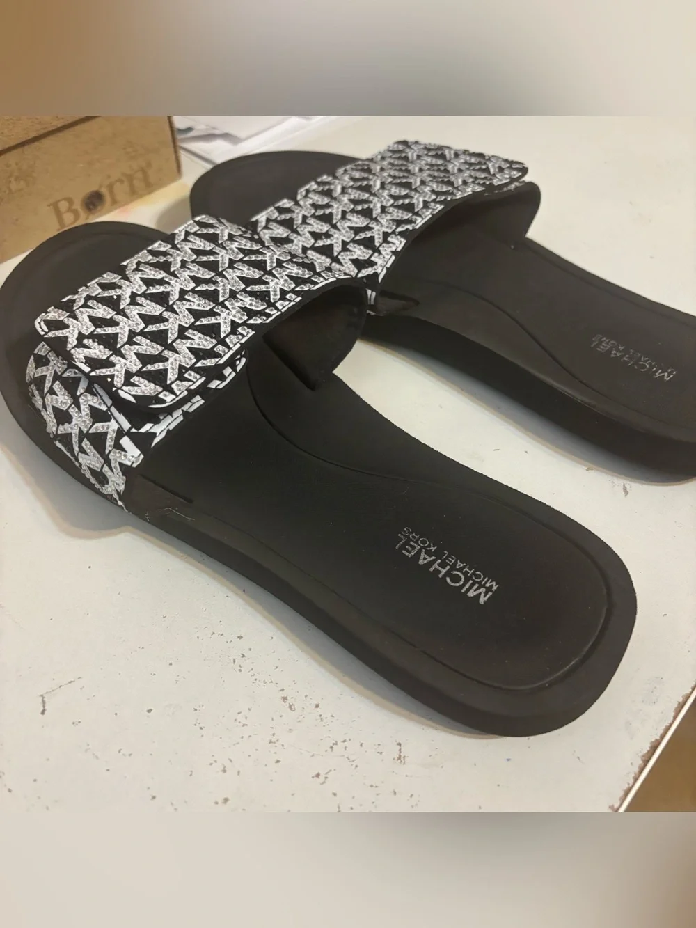 Michael Kors black & white slides featuring a signature logo print on the strap.